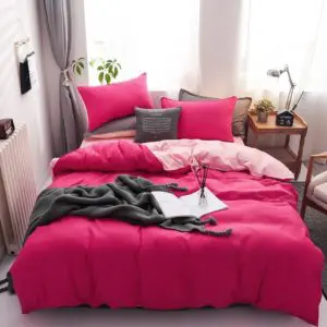 Parure de lit bicolore rose-framboise, bonne qualité et très confortable sur un lit dans une maison