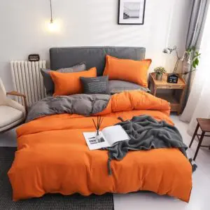 Parure de lit bicolore orange-grise. Bonne qualité, confortable et à la mode sur un lit dans une maison