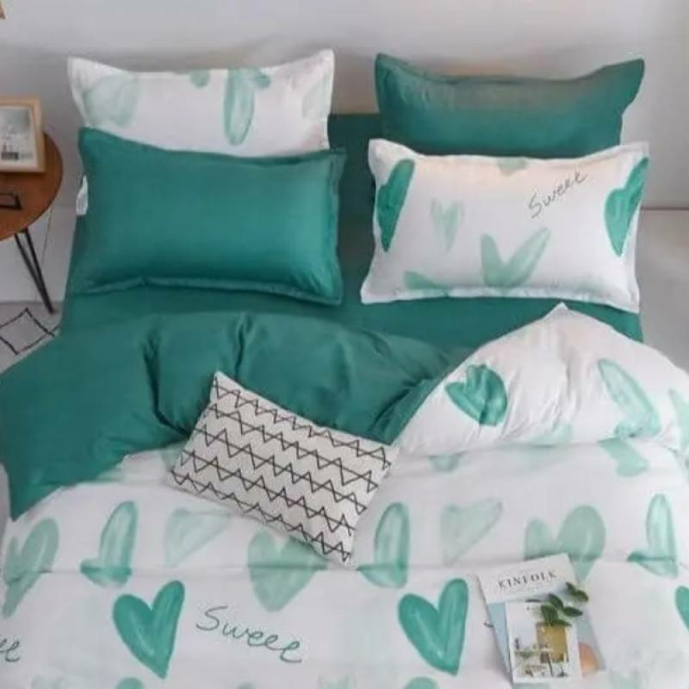 Parure de lit coeurs bleu-vert. Bonne qualité et très confortable sur un lit dans une maison.