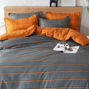 Parure de lit imprimé orange et grise, bonne qualité et très original sur un lit dans une maison.