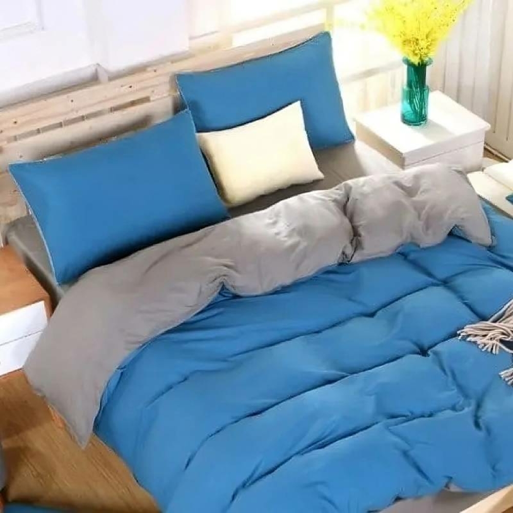 Parure de lit bicolore azure-grise. Bonne qualité et très confortable sur un lit dans une chambre.
