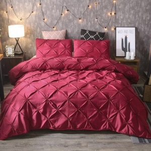 Parure de lit rouge à effet matelassé. Bonne qualité, confortable et à la mode sur un lit dans une maison