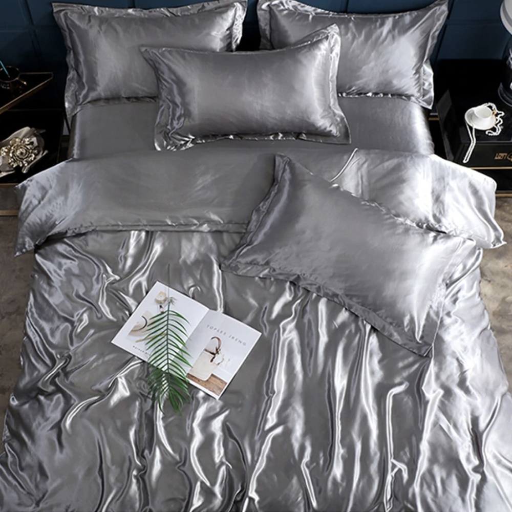 Parure de lit en satin de soie gris. B onne qualité, confortable et à la mode sur un lit dans une maison