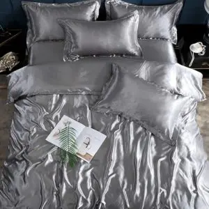 Parure de lit en satin de soie gris. B onne qualité, confortable et à la mode sur un lit dans une maison