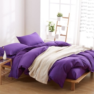 Parure de lit unie violet. Bonne qualité, confortable et à la mode sur un lit dans une maison