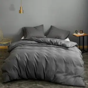 Parure de lit grise unie. Bonne qualité, confortable et à la mode sur un lit dans une maison