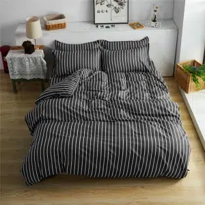Parure de lit rayée noir et blanche, bonne qualité et à la mode, sur un lit dans une maison