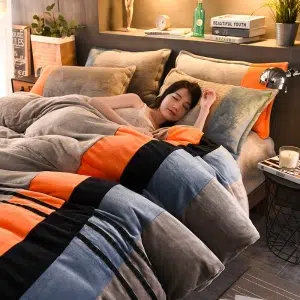 Parure de lit grise à rayures orange noir bleu. Bonne qualité, confortable et à la mode sur un lit dans une maison