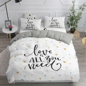 Parure de lit blanche inscription « Love is all you need ». Bonne qualité, confortable et à la mode sur un lit dans une maison