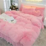 Ensemble de parure de lit. La parure est rose claire avec un effet fourure polaire.