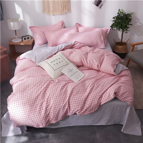 Parure de lit rose à motifs carreaux noirs. Bonne qualité, confortable et à la mode sur un lit dans une maison