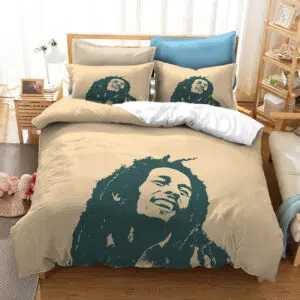 Dans une chambre le lit est décoré d'une parure à l'effigie de Bob Marley dessiné, de couleur beige, avec le visage du chanteur bob marley, les coussins sont assortis, à droite du lit il y a un banquette en bois avec les coussins blanc, et un meuble étagère en bois, à gauche du lit il y a une table de chevet en bois et des jouets