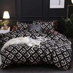 Parure de lit type scandinave de couleur noir et blanc avec des motifs carré avec un drap blanc posé dessus devant un mur noir