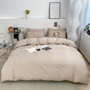 Parure de lit de couleur beige unie avec un magazine posée dessus dans une chambre de style scandinave au sol beige et mur blanc