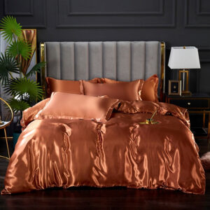 Parure de lit en satin de couleur orange unie avec une tasse de café posée dessus devant un mur noir et un sol noir