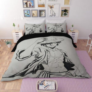 Dans une chambre, installée sur le lit et les oreillers, une parure complète à l'effigie du manga One Piece avec l'image du personnage Monkey D. Luffy en noir et blanc sur fond gris , de chaque côté du lit il y a une table de chevet blanche et carrée, au dessus du lit des affiches sont accrochées au mur et un tapis violet se trouve au sol