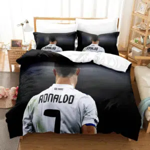 Parure de lit grise avec la photo de cristiano ronaldo vu de dos et dont on peut lire son nom sur le maillot de football , dans une chambre avec une table de chevet en bois à gauche et un meuble étagère à gauche