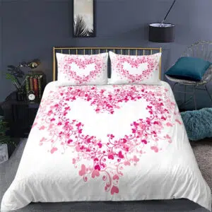 parure de lit avec un cœur rose formé d'autres petits coeur roses sur fond blanc, à gauche une table de chevet, à droite un siège