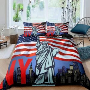 Parure de lit New York avec la Statue de la Liberté devant et des drapeaux américains derrière, les lettres N et Y en rouge sur la gauche. Deux coussins assortis sur un lit double. Au fond, une grande fenêtre et une chaise en métal sur la droite.