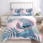 Parure de lit Stitch au design tropical sur fond rose avec des feuilles de palmiers vertes. Les deux coussins sont assortis à la housse de couette. L'ensemble est sur un lit double avec une tête de lit blanche, une table de chevet de chaque côté avec des objets de décoration.