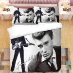 Parure de lit Johnny Hallyday en noir et blanc de l'artiste jeune en costume sur la droite et avec une guitare sur la gauche. Les deux coussins sont assortis à la housse de couette et sont tous posés sur un lit double.