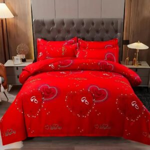 Parure de lit romantique rouge vif avec des coeurs et inscriptions brillantes. La housse de couette est assorties à deux coussins. L'ensemble se trouve sur un lit double dans une chambre avec une tête de lit matelassée marron. Une table de chevet de chaque côté du lit avec une lampe de chevet allumé.