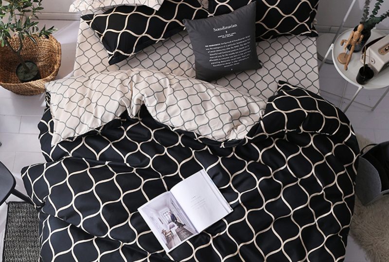 Parure de lit scandinave avec motif de nid d'abeille en noir et blanc avec un livre ouvert posé dessus