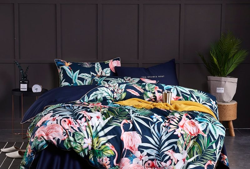 Parure de lit bleu nuit motifs fleurs et flamant rose. Bonne qualité, confortable et à la mode sur un lit dans une maison