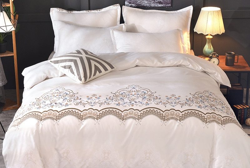 Parure de lit blanche dentelle florale. Bonne qualité, confortable et à la mode sur un lit dans une maison