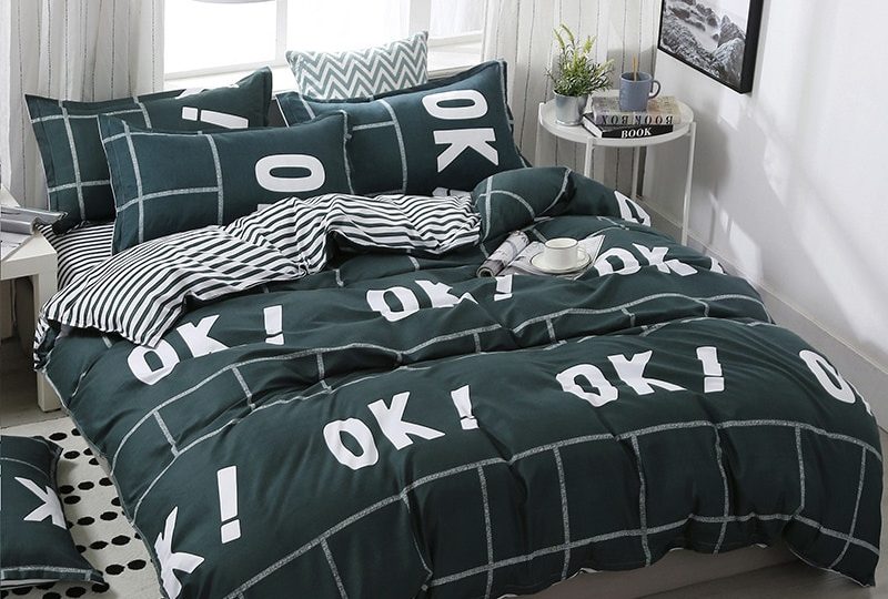 Parure de lit vert foncé avec inscription OK. Bonne qualité, confortable et à la mode sur un lit dans une maison