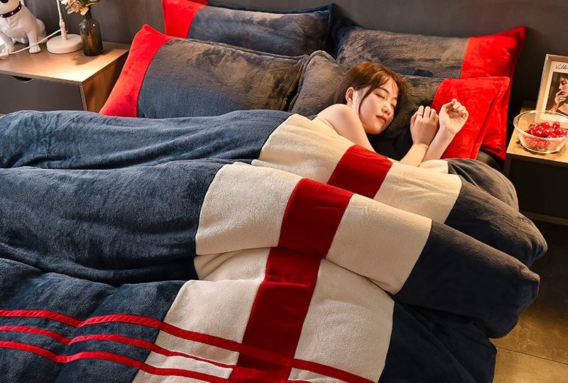 Parure de lit grise à rayures blanc et rouge. Bonne qualité, confortable et à la mode sur un lit dans une maison