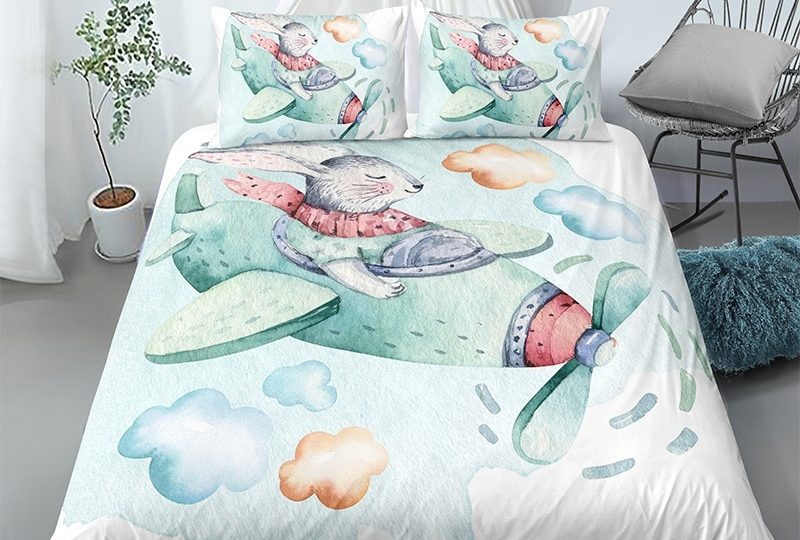 Parure de lit blanche motif lapin pilotant un avion. Bonne qualité, confortable et à la mode sur un lit dans une maison