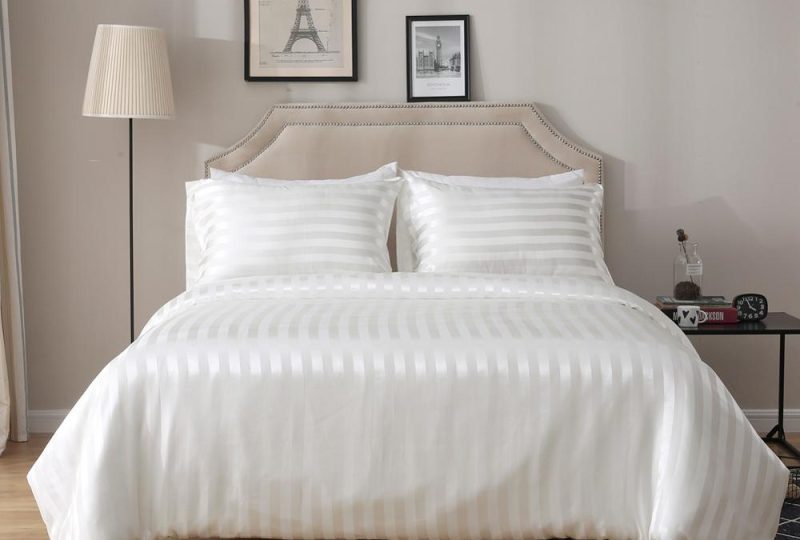 Parure de lit blanche rayée ton sur ton. Bonne qualité, confortable et à la mode sur un lit dans une maison