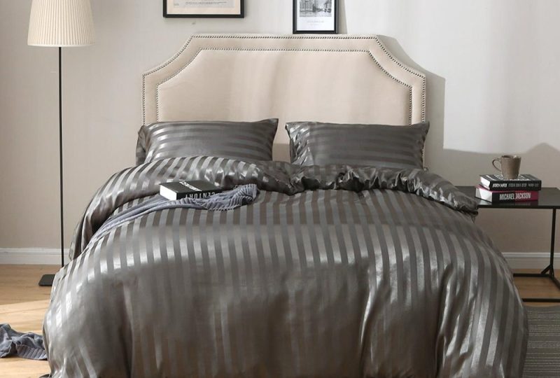 Parure de lit grise rayée ton sur ton. Bonne qualité, confortable et à la mode sur un lit dans une maison