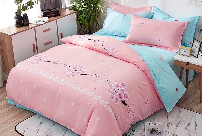 Parure de lit fleurie rose en coton. Bonne qualité, confortable et à la mode sur un lit avec un tapis dans une maison