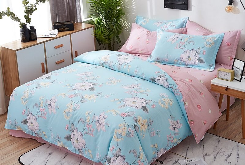 Parure de lit bleue et rose motif fleurs. Bonne qualité, confortable et à la mode sur un lit dans une maison