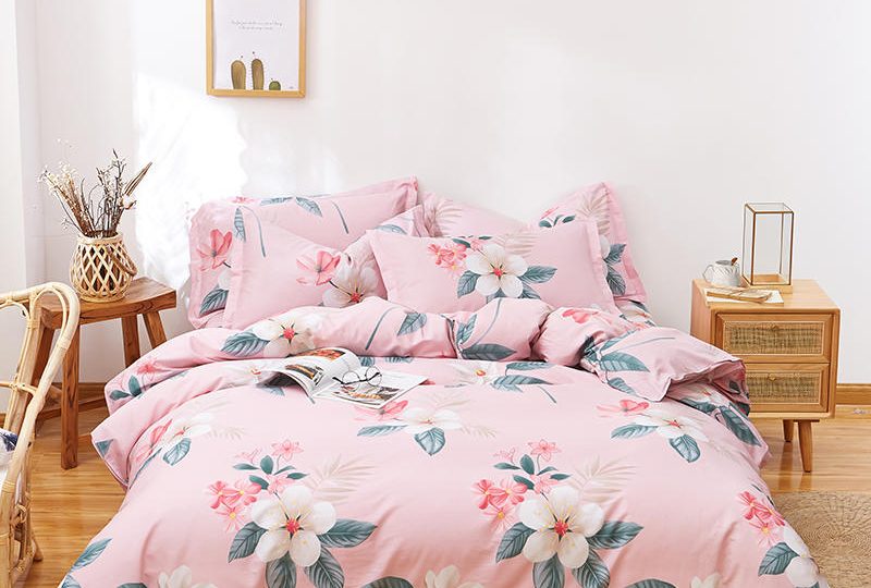 Parure de lit rose avec motif fleurs en coton. Bonne qualité, confortable et à la mode sur un lit dans une maison
