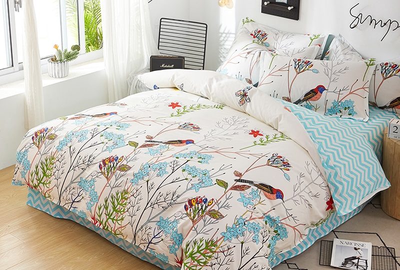 Parure de lit blanche en coton à motif oiseaux et fleurs. Bonne qualité, confortable et à la mode sur un lit dans une maison