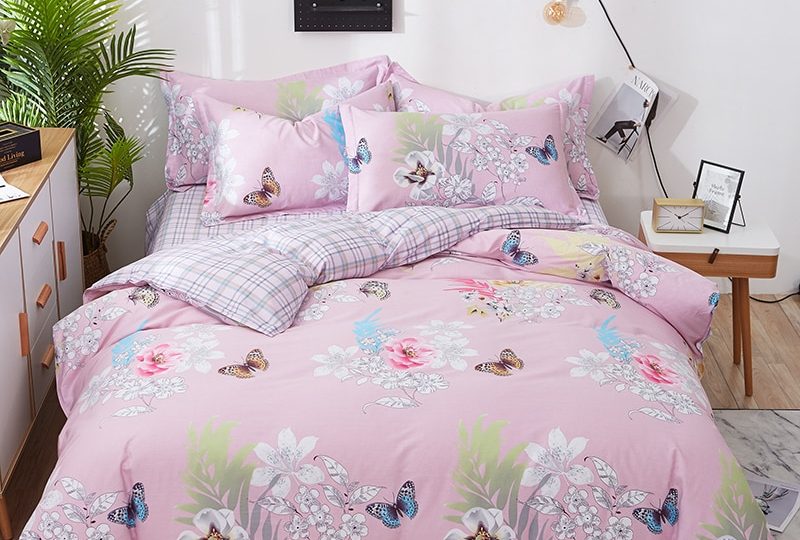 Parure de lit rose motif fleurs et papillons. Bonne qualité, confortable et à la mode sur un lit dans une maison