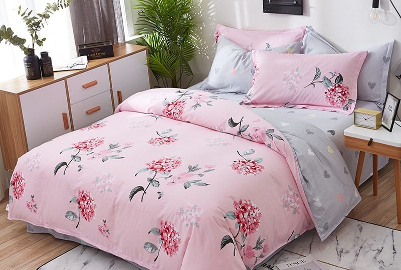 Parure de lit rose et grise en coton imprimé fleuri. Bonne qualité, confortable et à la mode sur un lit dans une maison