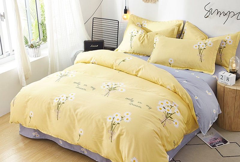 Parure de lit jaune motif fleurs blanches. Bonne qualité, confortable et à la mode sur un lit dans une maison