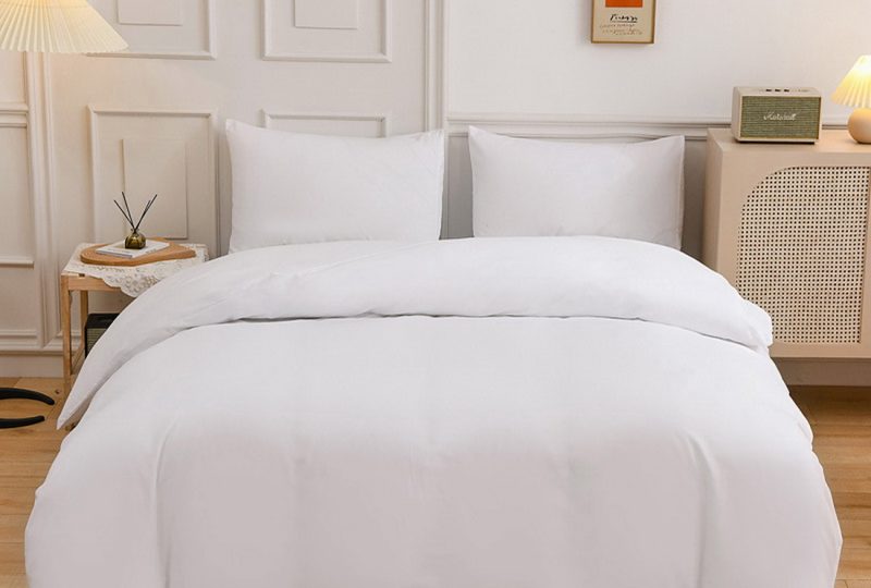 Parure de lit de couleur beige dans une chambre au style scandinave avec du parquet et un mur blanc