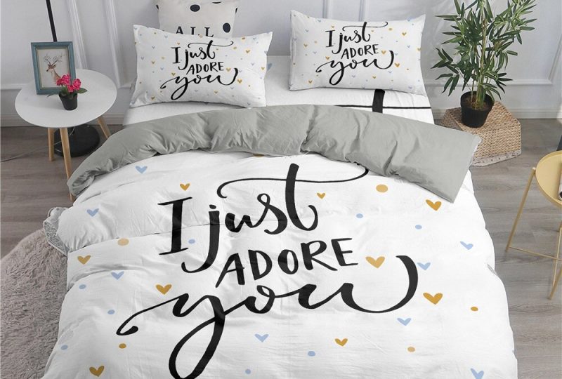 50215-c848ca.jpg Parure de lit blanche avec inscription « I just adore you ». Bonne qualité, confortable et à la mode sur un lit dans une maison