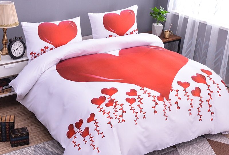 Parure de lit blanche à motif cœurs rouges. Bonne qualité, confortable et à la mode sur un lit dans une maison