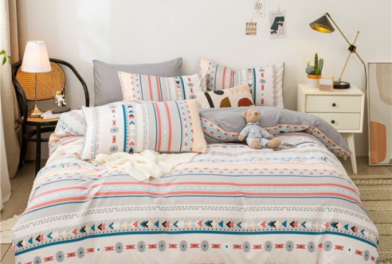 Parure de lit bohème grise à rayures. Bonne qualité, confortable et à la mode sur un lit dans une maison