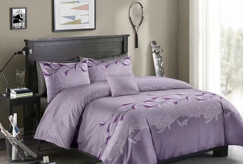 Parure de lit violette à motif floral blanc. Bonne qualité, confortable et à la mode sur un lit dans une maison