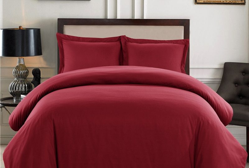 Parure de lit unie rouge confortable. Bonne qualité, confortable et à la mode sur un lit dans une maison