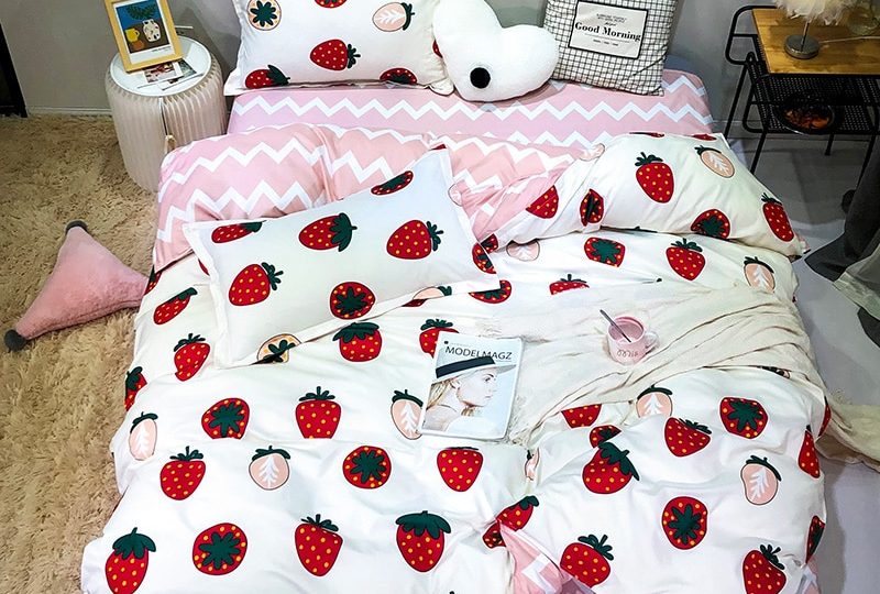 Parure de lit blanche à motif fraise. Bonne qualité, confortable et à la mode sur un lit dans une maison