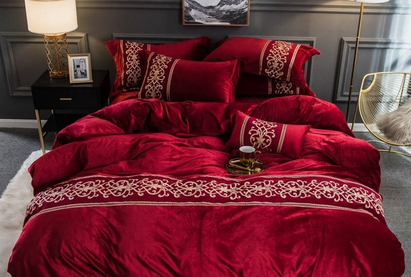 Parure de lit rouge molletonné brodée. Bonne qualité, confortable et à la mode sur un lit dans une maison