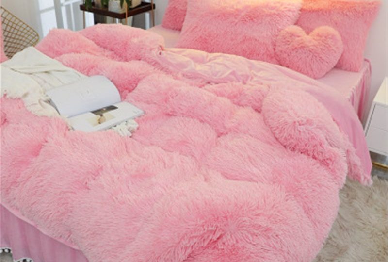 Ensemble de parure de lit. La parure est rose claire avec un effet fourure polaire.